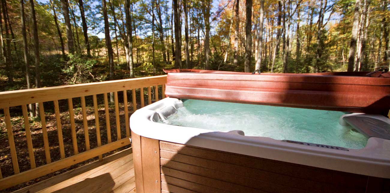 A hot tub sits ready for guests on the deck at Country Road Cabins.