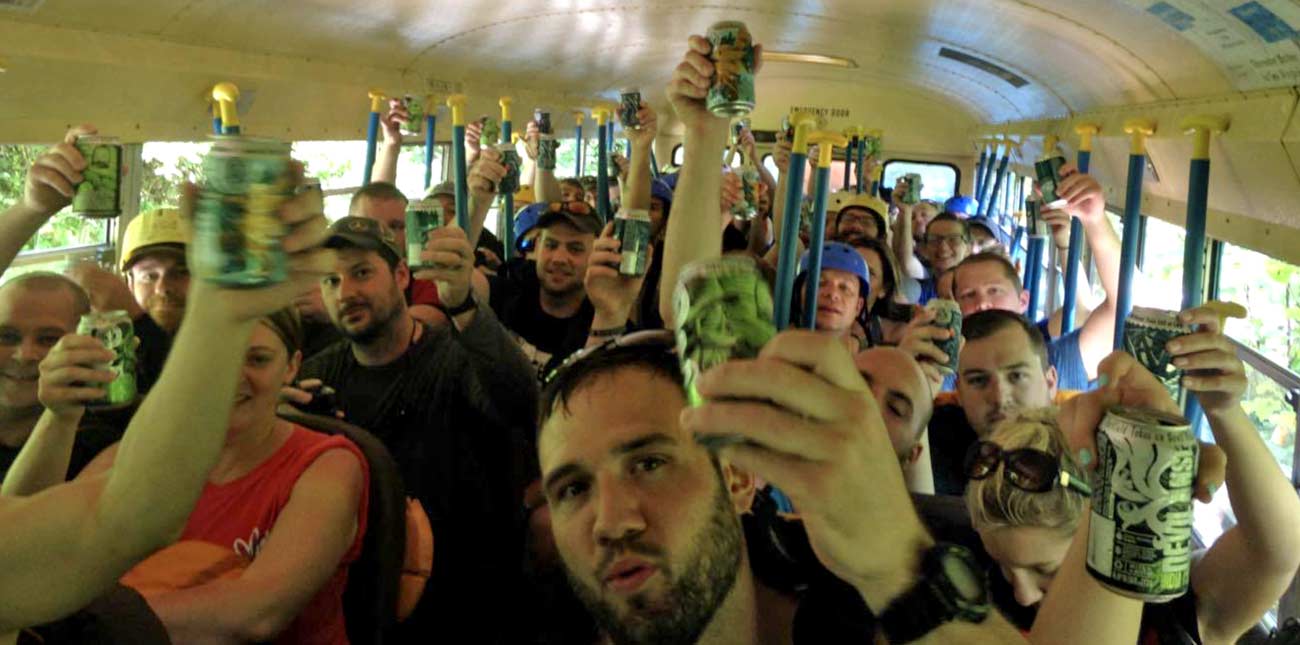 A group of ACE whitewater rafters celebrate their rafting trip by toasting cans of GVBC Devil Anse IPA on the ACE bus.