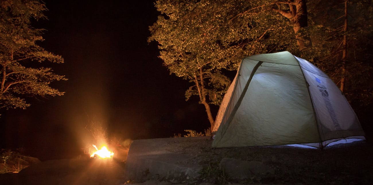 An overnight campsite glows next to the fire under the stars on a camping trip with ACE Adventure Resort in West Virginia.