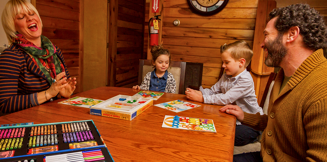 A family plays games inside their winter lodging cabin at ACE Adventure Resort in the New River Gorge.