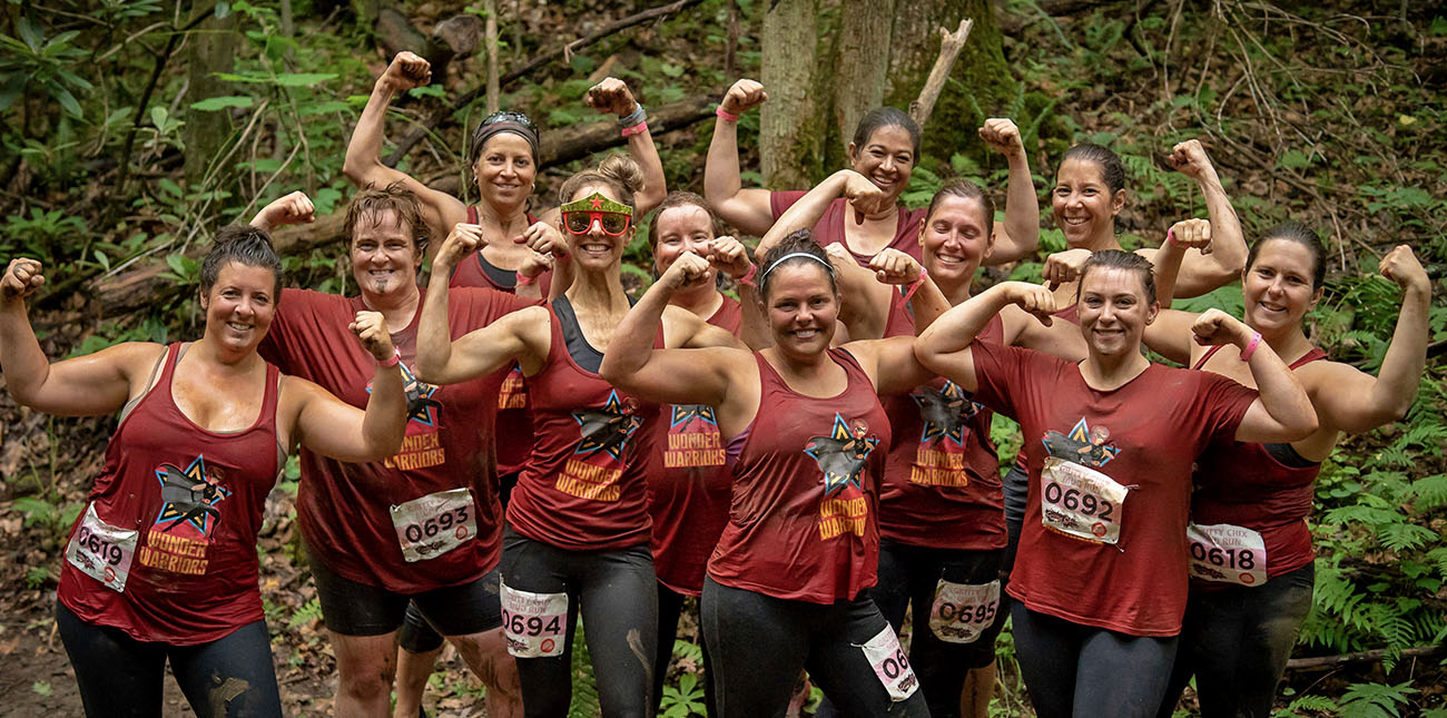 A group of Gritty Chix pose on the mud course during the Gritty Chix Mud Run at ACE Adventure Resort in the New River Gorge, WV.