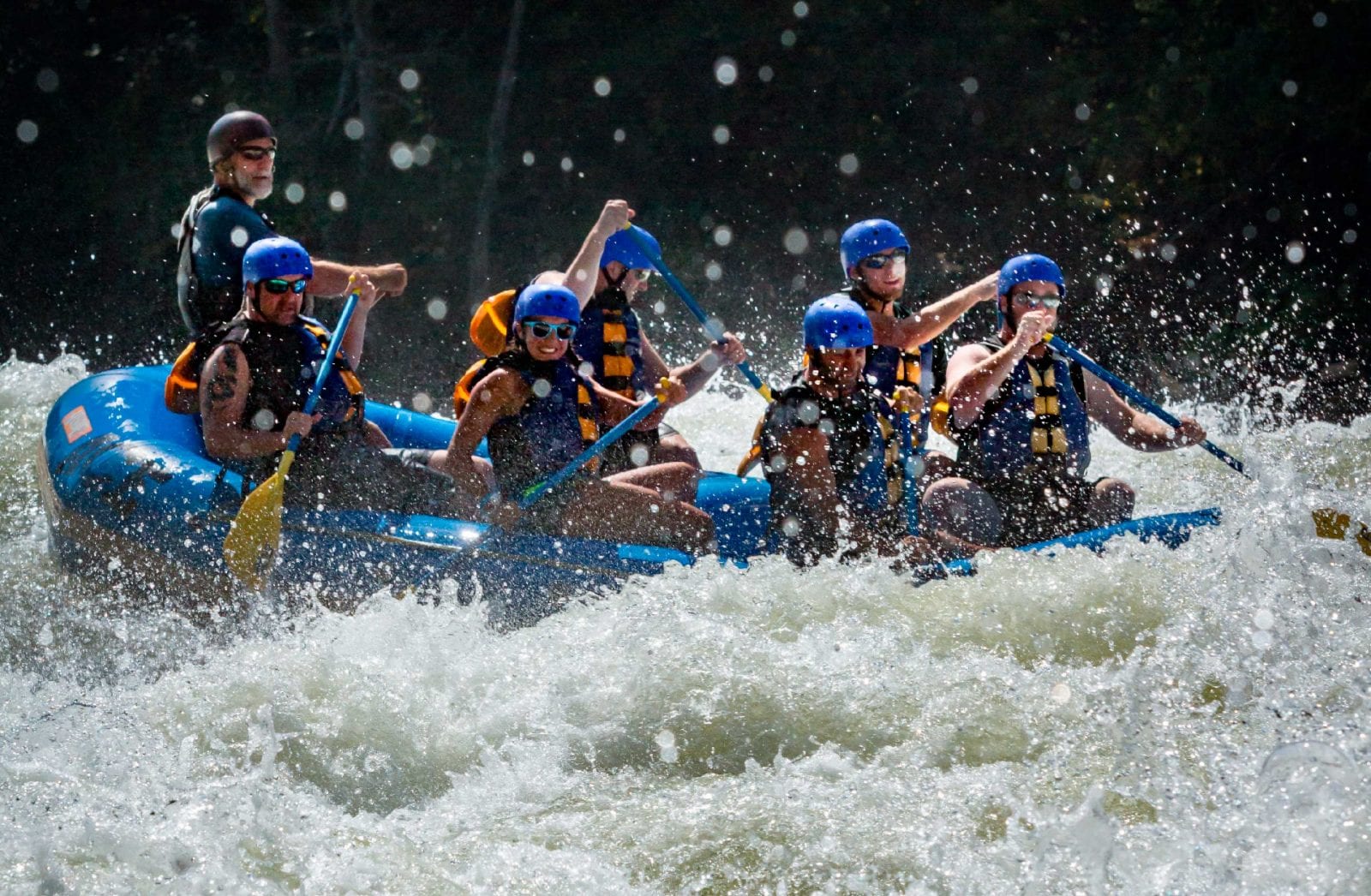 A team smiles and paddles during a day of west virginia whitewater rafting on the upper gauley river with ace adventure resort.