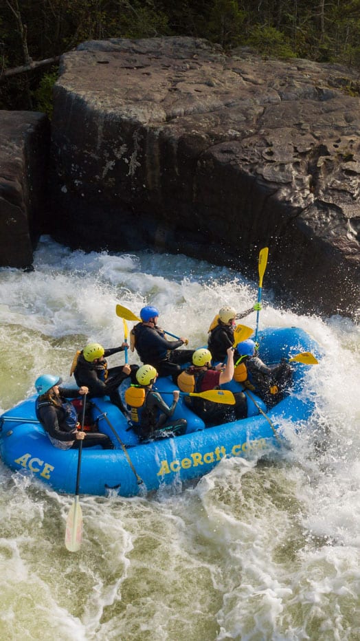 An ACE raft passes the house size boulder called Pillow Rock on an Upper Gualey river rafting trip in West Virginia.