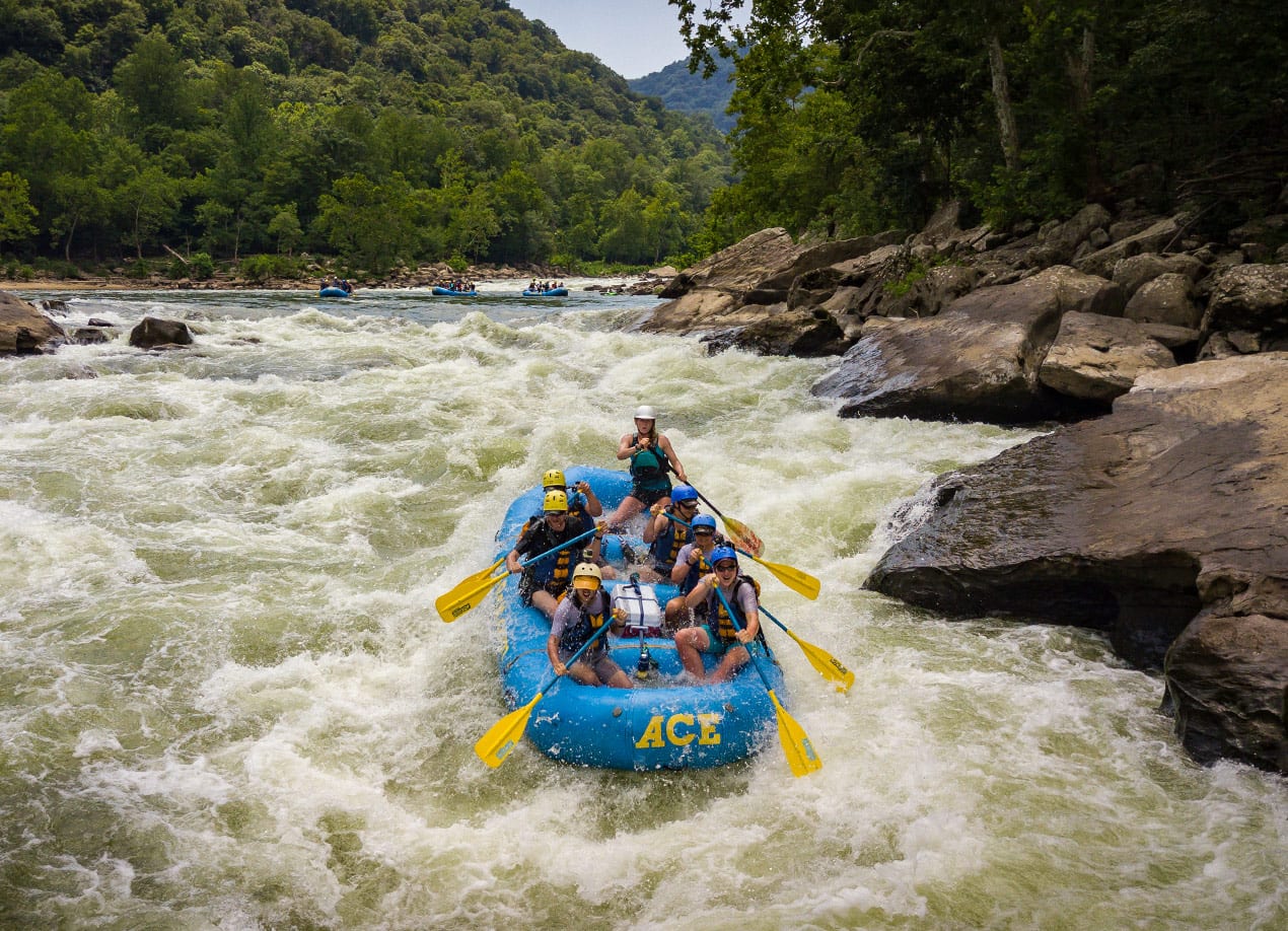 Several boats on a new river gorger rafting trip run the keeney's rapids with a mountain backdrop.