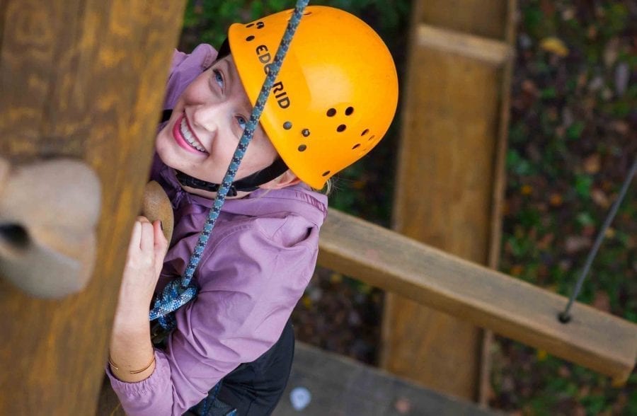 A girl climbing up the alpine tower ropes on the Team Challenge Course at ACE Adventure Resort