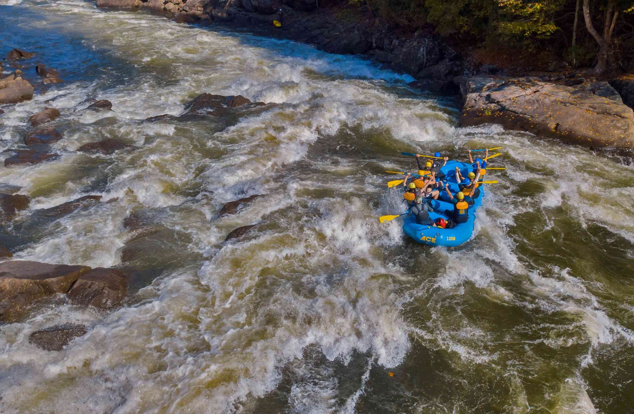 A 6 person raft appears tiny in the massive waves of the Upper Gauley on a Gauley River rafting trip with ACE Adventure Resort.