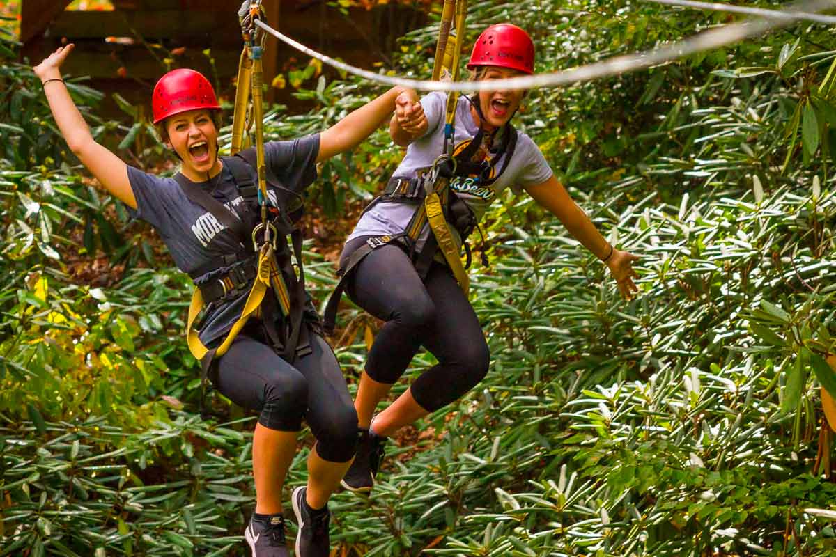 Two friends zip together on a tandem run on the new river gorge zip line course.