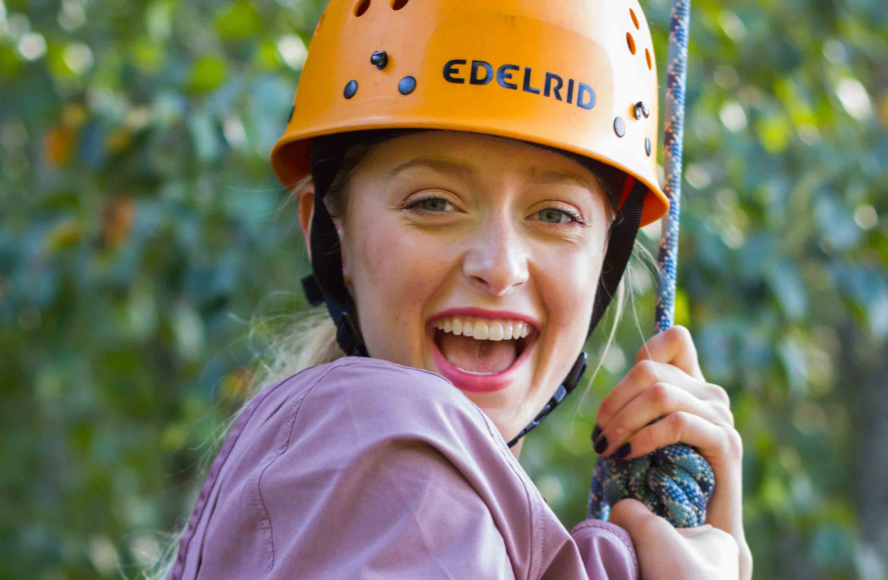 A girl smiles while harnessed into the rope climbing system on the Team Challenge Course at ACE Adventure Resort.