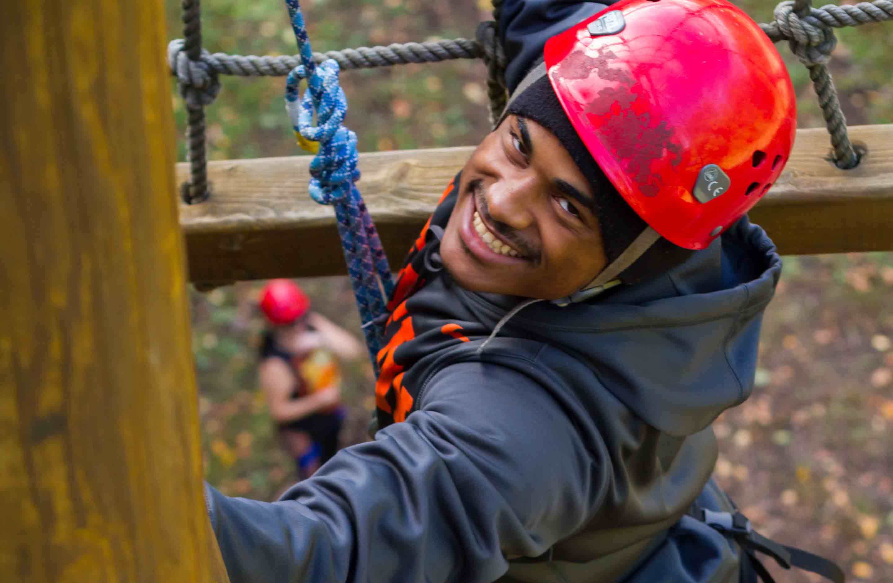 A college student on a group trip with ACE Adventure Resort ascends the ropes on the Team Challenge Course.