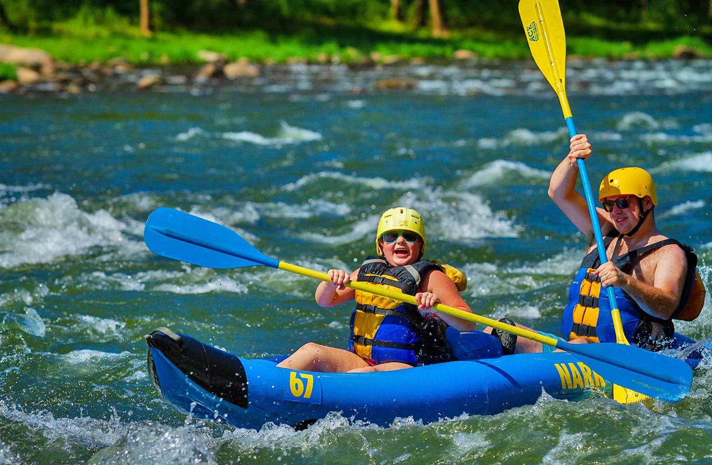 A child smiles on a kid friendly rafting trip on the upper new river gorge with their father.