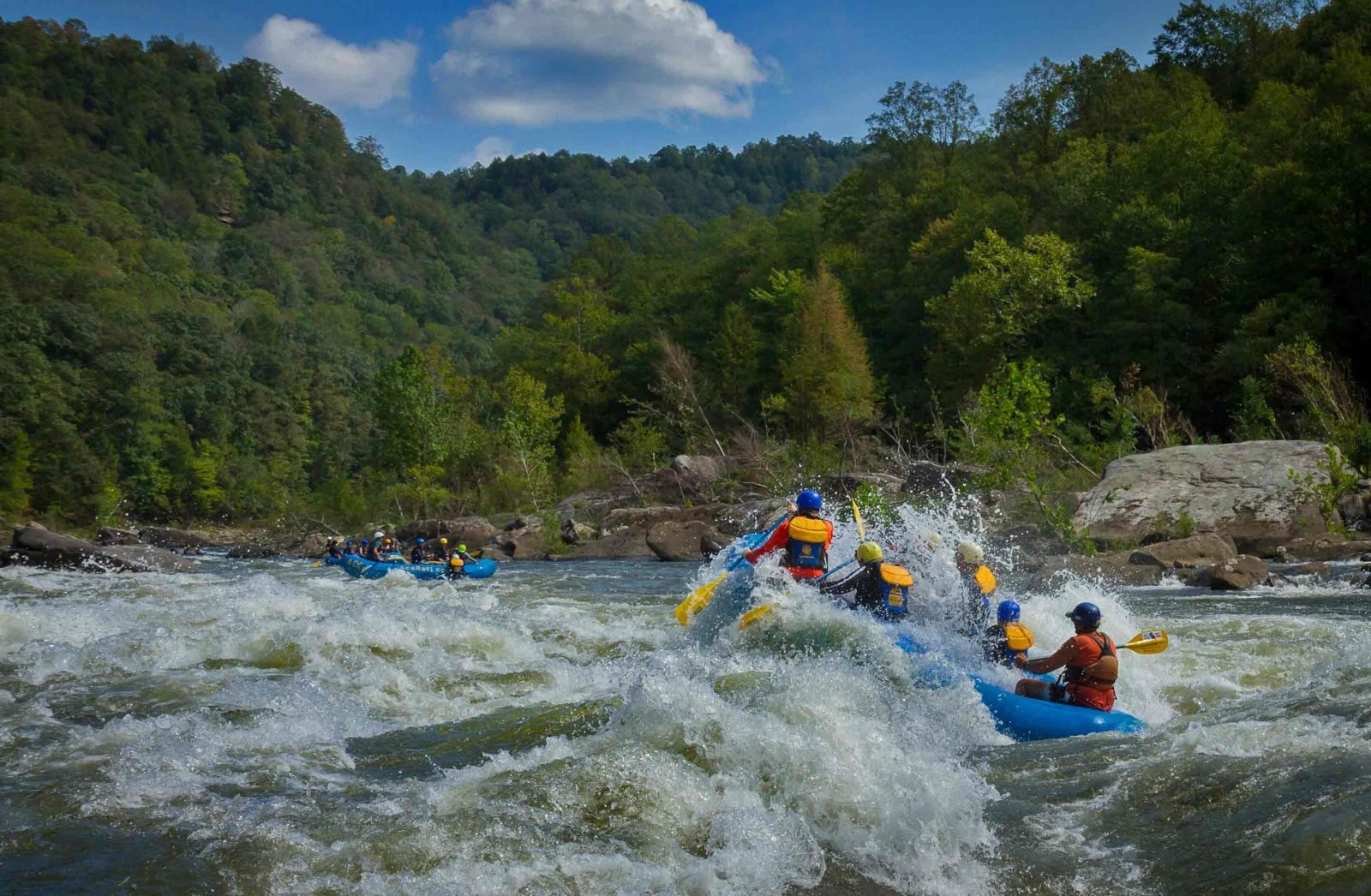 An ACE raft bursts through a wave on the Lower Gauley River whitewater rafting in West Virginia.