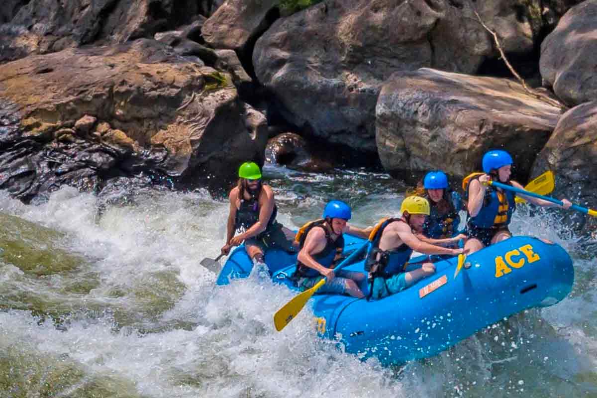 A small raft crashes through waves in Lower Keeney rapid on a New River Gorge white water rafting trip in West Virginia with ACE Adventure Resort