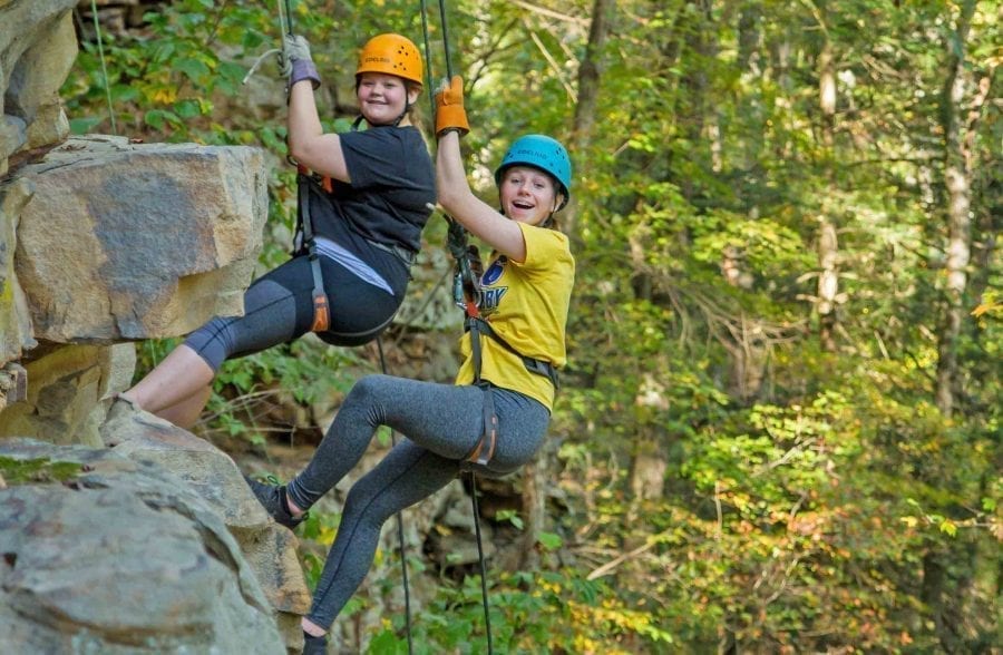 Two students rappel down a cliff in the Upper New River Gorge, on ACE's private climbing route.