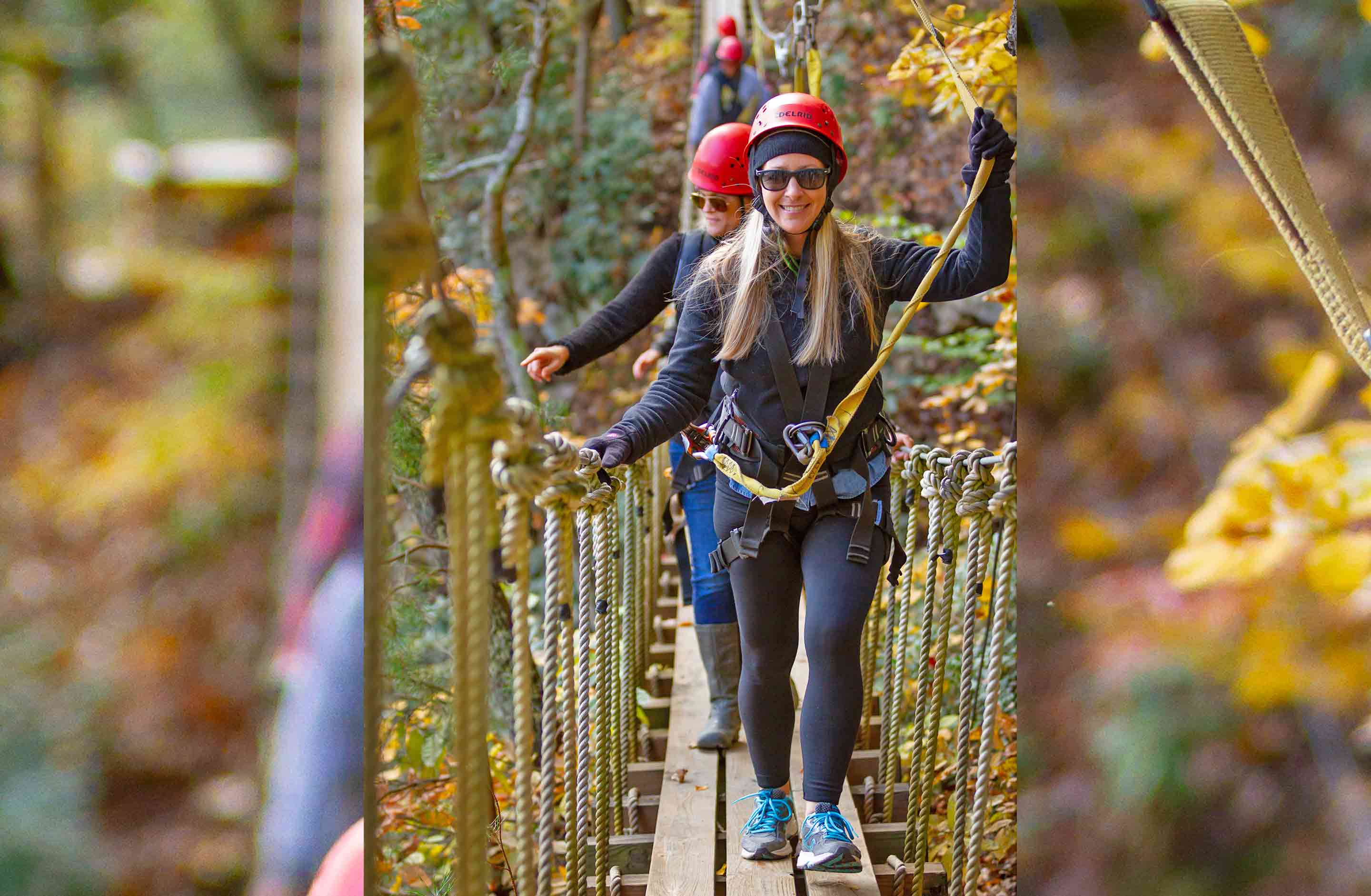 A group crosses the swinging rope bridge in the tree tops at the fall zip line course at ACE Adventure Resort in the New River Gorge, WV.