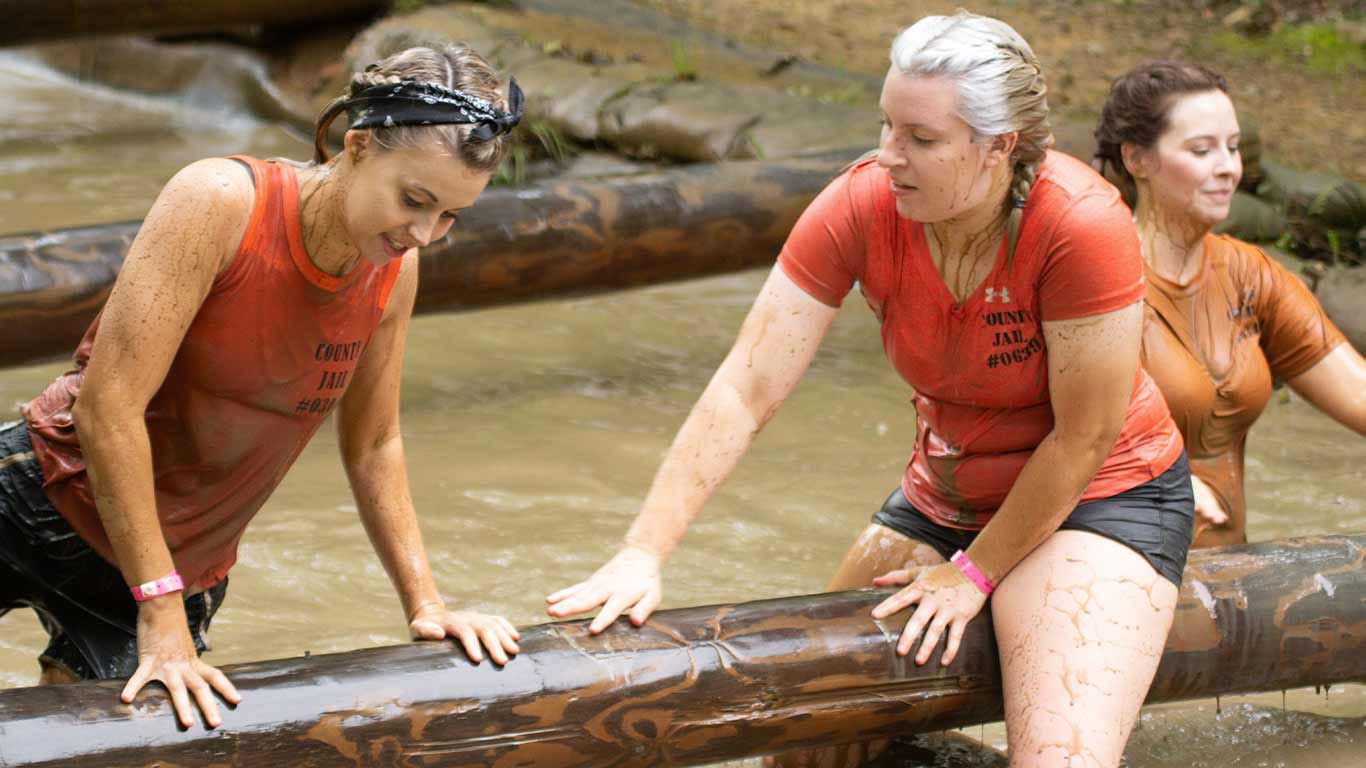 Runners in mud pit smiling