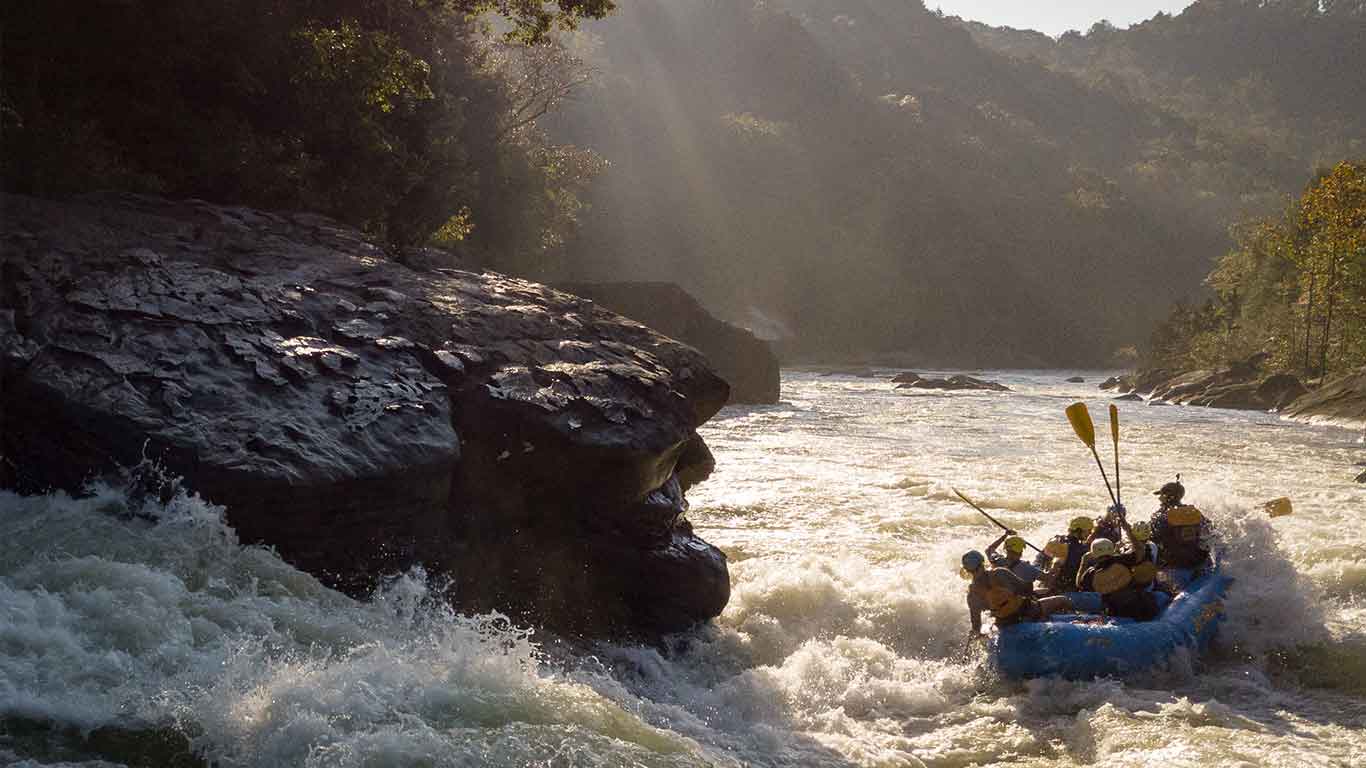 Photo of guests rafting the Upper Gauley with sun shining in the background