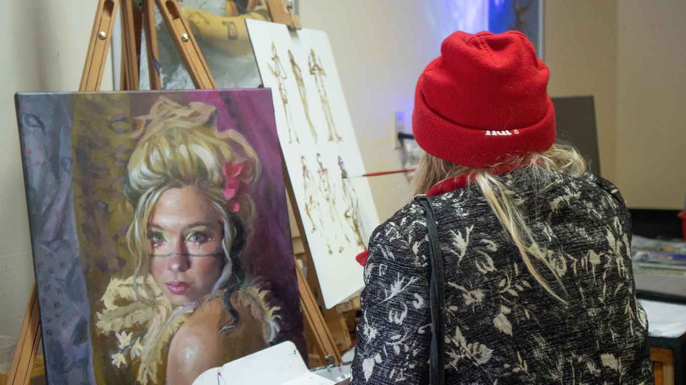 Girl painting a blonde figure at Pigment Sanctuary Art Party