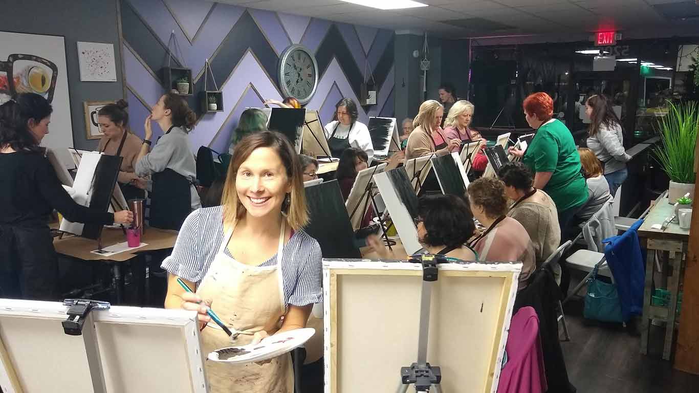 Teacher from Wild and Wonderful Art party posing while painting