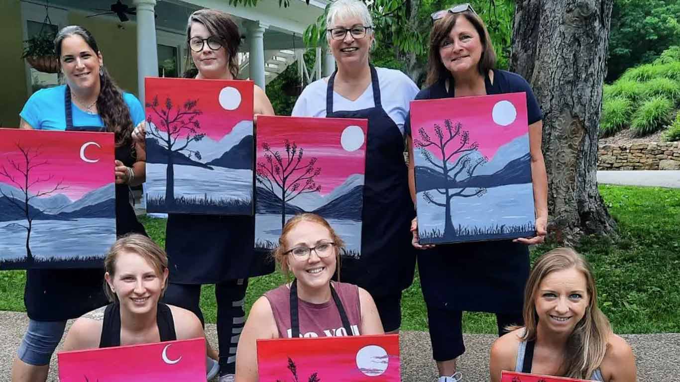 Group showing their paintings from paint and sip art party