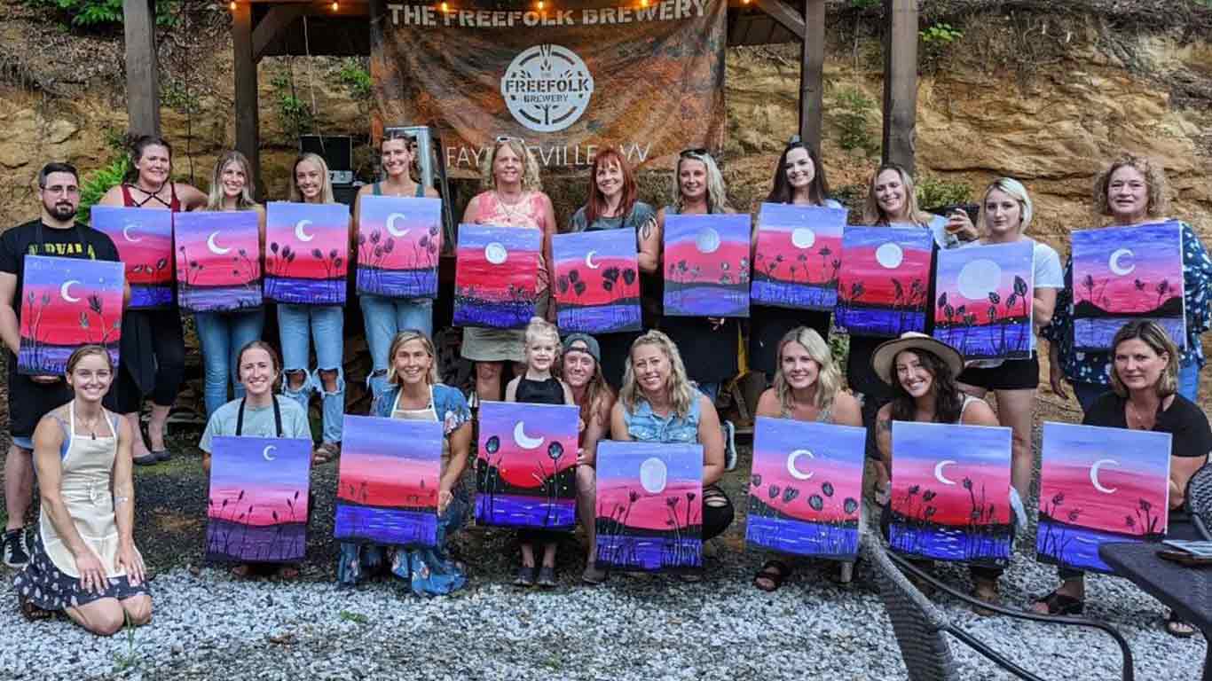 Group showing off paintings from paint and sip art party