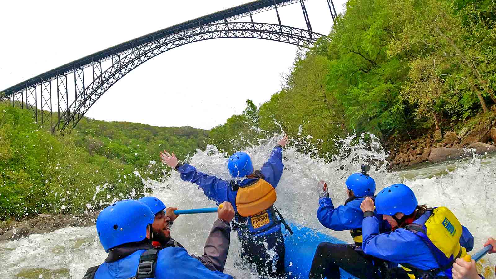 A group of rafters enjoy new river gorge white water rafting in fayette staction rapid beneath the new river gorge bridge in the national park.
